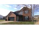 View of a two-story home with a brick and vinyl facade, a two-car garage, and a well-manicured lawn at 6812 Cadwell Cir, Indianapolis, IN 46237