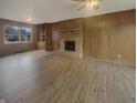 Living room featuring wood paneling, a brick fireplace, and wood-look flooring at 8507 Palm Ct, Indianapolis, IN 46219