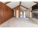 Spacious living room with wood-paneled walls, beamed ceilings, a stone fireplace, and neutral carpet at 953 S 5Th St, Noblesville, IN 46060
