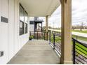 Spacious covered porch with concrete flooring, black iron railings, and views of the surrounding neighborhood at 11505 Langton Walk, Zionsville, IN 46077