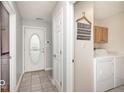 Hallway view featuring a white front door, tile flooring, and a laundry room at 136 Meadow Glen Dr, Avon, IN 46123