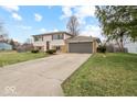 Split-level home showcasing a front yard, a two-car garage, and a combination of stone and siding at 4448 Aristocrat Cir, Indianapolis, IN 46235