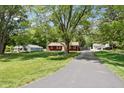 View of a home across a grassy lawn with mature trees and a long driveway at 4754 E 64Th St, Indianapolis, IN 46220