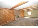 Spacious living room featuring brick fireplace, wood paneled wall, exposed beams, and window with natural light at 4958 E County Road 100 N, Avon, IN 46123