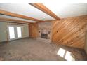 Spacious living room with brick fireplace, wood paneled wall, exposed beams, and glass door leading to outside at 4958 E County Road 100 N, Avon, IN 46123