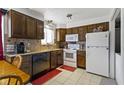 Traditional kitchen with dark wood cabinets, white appliances, neutral countertops and tile flooring at 7965 Benjamin Dr, Lawrence, IN 46226