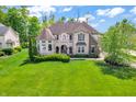 A beautiful home with a lush green lawn, a turret and a mix of brick and stone accents at 10792 Harbor Bay Dr, Fishers, IN 46040
