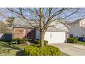 Well-maintained home featuring a brick exterior, white garage door, and mature trees in the front yard at 11930 Titania Cir, Indianapolis, IN 46236
