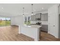 Modern kitchen with stainless steel appliances, gray cabinets, an island, and wood floors at 15982 Meadow Frost Ct, Fishers, IN 46037