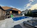 An in-ground swimming pool surrounded by a wooden deck and patio furniture under a clear, blue sky at 1740 Golden Field Dr, Greenwood, IN 46143