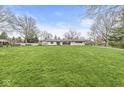 Expansive green lawn with a single story home and a view of mature trees in the background at 671 Spring Hills Dr, Zionsville, IN 46077