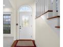 Close-up of a front door, decorative glass, and hardwood flooring in the foyer at 7845 W Hillside Dr, Columbus, IN 47201