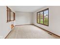 Spacious room with carpet, large window, wood trim, and staircase at 10673 Rolling Springs Dr, Indianapolis, IN 46234