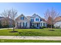 Beautiful two-story home boasts manicured front lawn and stone details and a blossoming tree at 13875 Ambria Dr, McCordsville, IN 46055