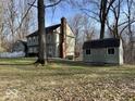 The backyard with mature trees, a storage shed, and a charming view of the home's exterior at 155 Boring Pl, Martinsville, IN 46151