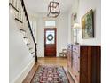 Inviting entryway featuring hardwood floors, staircase, paneled wood door and decorative light fixture at 450 W Ash St, Zionsville, IN 46077