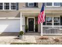 Inviting front porch featuring an American flag, a black door, and potted greenery at 5687 N Plymouth Ct, McCordsville, IN 46055