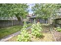Backyard featuring mature trees, a garden area, grass and a walkway to the back door at 615 E Morris St, Indianapolis, IN 46203