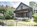 Charming home featuring a covered porch, gray siding, a red door, and lush landscaping at 615 E Morris St, Indianapolis, IN 46203