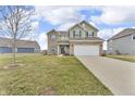 Inviting two-story home featuring a two-car garage, green siding and brick accents at 6180 N Rosewood Dr, McCordsville, IN 46055