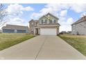 Inviting two-story home featuring a two-car garage, green siding and brick accents at 6180 N Rosewood Dr, McCordsville, IN 46055
