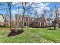 Traditional brick house with black shutters, a green lawn, mulch beds and mature trees in a suburban neighborhood at 6545 Briarwood Pl, Zionsville, IN 46077