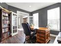 Well-lit home office with hardwood floors, a large desk, ample bookshelf space, and double doors at 6545 Briarwood Pl, Zionsville, IN 46077