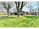 View of the front of the house shows a well kept lawn and mature trees at 695 Valley Oaks Rd, Greenwood, IN 46143