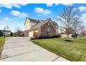 Charming home featuring a brick exterior, attached garage, well-maintained lawn, and neat landscaping at 9253 Windrift Way, Zionsville, IN 46077