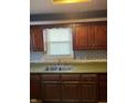 Classic kitchen sink and cabinets with green countertop, floral wallpaper, and window at 930 N Ritter Ave, Indianapolis, IN 46219