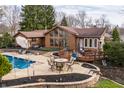 Backyard featuring a pool, patio, and deck surrounding a brown home with mature trees at 10373 Briar Creek Pl, Carmel, IN 46033