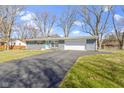Inviting ranch-style home featuring a spacious driveway, attached garage, and attractive stone facade at 10427 N Delaware St, Carmel, IN 46280