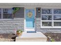 Close-up of a stylish light blue front door with decorative sunflower wreath and well-kept entryway at 10427 N Delaware St, Carmel, IN 46280