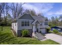 Beautifully landscaped front yard leads to an updated home with a white garage door and mature shade trees at 5836 Andover Rd, Indianapolis, IN 46220