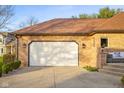Attached garage with a white door and a paved driveway surrounded by green landscaping at 6043 Acorn Dr, Columbus, IN 47201