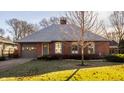 Charming red brick home with gray shutters, attached garage and well maintained lawn at 7021 Warwick Rd, Indianapolis, IN 46220