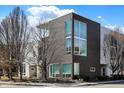 Street-level view of a modern townhome with a combination of dark brick and white siding, framed by bare trees against a blue sky at 932 Broadway St # 15, Indianapolis, IN 46202