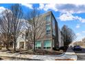 Contemporary townhome features striking dark brick and white siding, complemented by large windows and mature trees at 932 Broadway St # 15, Indianapolis, IN 46202
