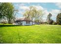 Quaint single-story house surrounded by a lush green lawn and mature trees at 1821 E Stop 10 Rd, Indianapolis, IN 46227