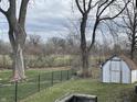 Spacious backyard featuring a chain-link fence, storage shed, mature trees, and plenty of green space at 1835 Carpenter Cir, Indianapolis, IN 46203