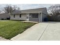 Cozy single-story home with a well-manicured lawn, gray siding, and a concrete driveway at 2638 Calbert Dr, Indianapolis, IN 46219