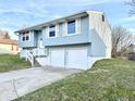 Blue two-story home featuring a two-car garage, staircase, and well-maintained yard on a clear day at 5608 Lunsford Dr, Indianapolis, IN 46237