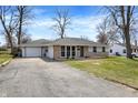 Ranch home features an attached garage, long driveway, and manicured lawn at 5887 Meadowlark Dr, Indianapolis, IN 46226