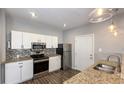 Well-lit kitchen featuring white cabinets, stainless steel appliances, granite countertops, and wood-look flooring at 952 E 34Th St, Indianapolis, IN 46205