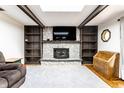 Cozy living room with a stone fireplace, wood beams, built-in shelving, and hardwood floors at 9619 E Southport Rd, Indianapolis, IN 46259