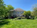 Expansive backyard featuring a beautiful white brick home with a deck, lush landscaping, and green grass at 11967 Windpointe Pass, Carmel, IN 46033