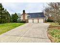 Spacious three-car garage with a long driveway, surrounded by lush greenery and mature trees at 12917 Brighton Ln, Carmel, IN 46032