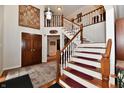 Inviting foyer with wooden staircase, detailed rug, and decorative wall tapestry, creating a grand entrance at 12917 Brighton Ln, Carmel, IN 46032