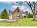 Charming brick home with a three-car garage, lush lawn and mature landscaping at 12917 Brighton Ln, Carmel, IN 46032