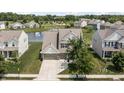Aerial view of a traditionally styled home with a pond, manicured lawn, mature trees, and multi-car garage at 12959 Balfour Rd, Fishers, IN 46037